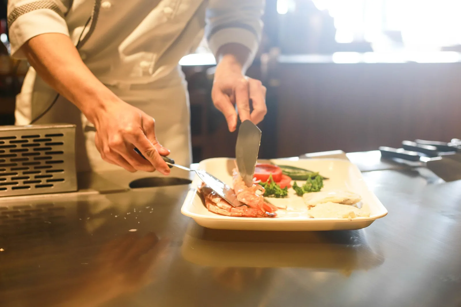 Profesional de cocina terminando la presentación de un plato con verduras
